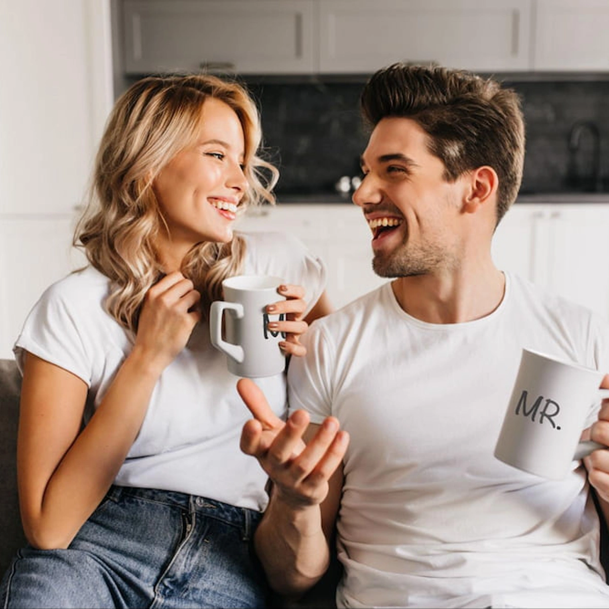 Happy couple enjoying coffee together with personalized Mr. and Mrs. mugs in their new home