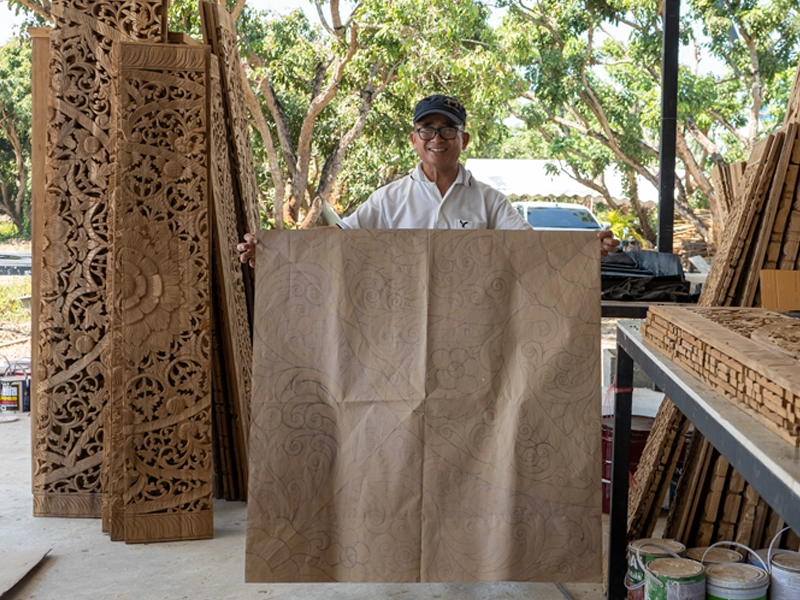Artisan smile holding drawing of carved headboard design