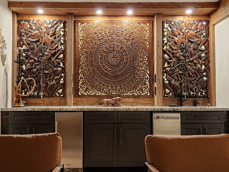 Hand-carved teak wall art centerpiece with side panels in a modern living space