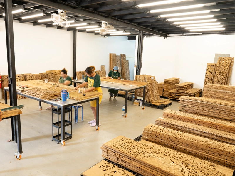 Siam Sawadee artisans refining teak wall art panels in workshop