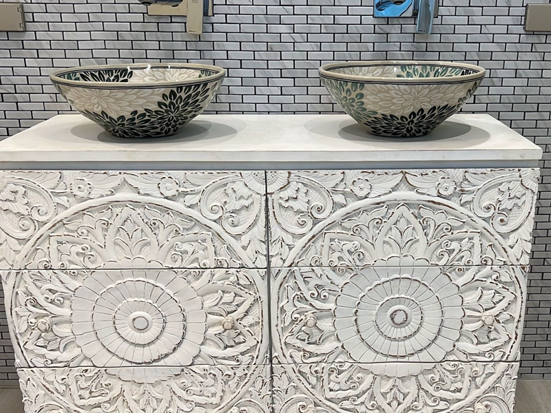 Handcrafted carved teak vanity with double basins in a bathroom setting